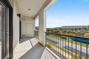 The view from the balcony of an apartment with a view of a pool and trees